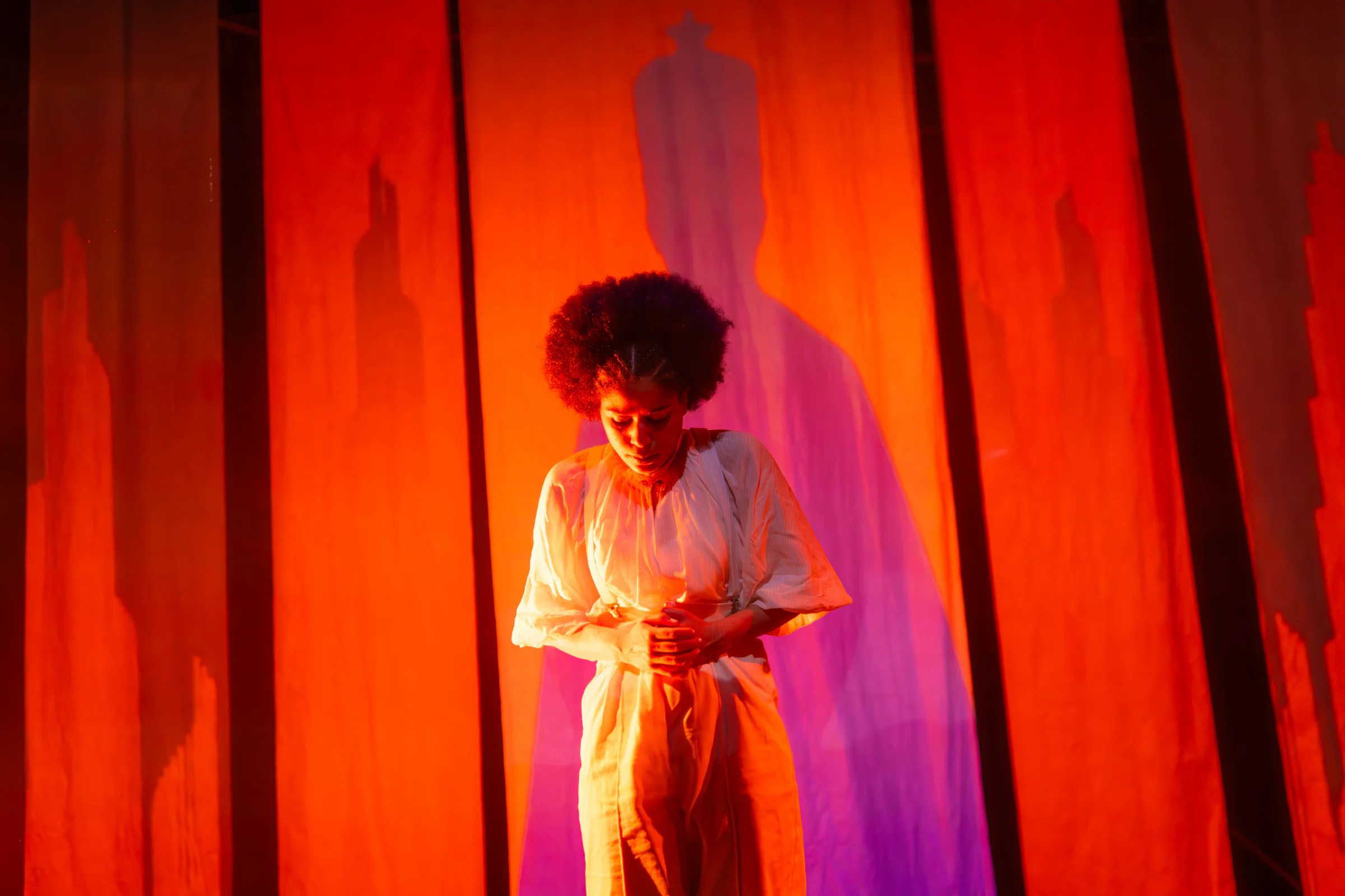 Fay Guiffo performs within vivid red and magenta stage light.