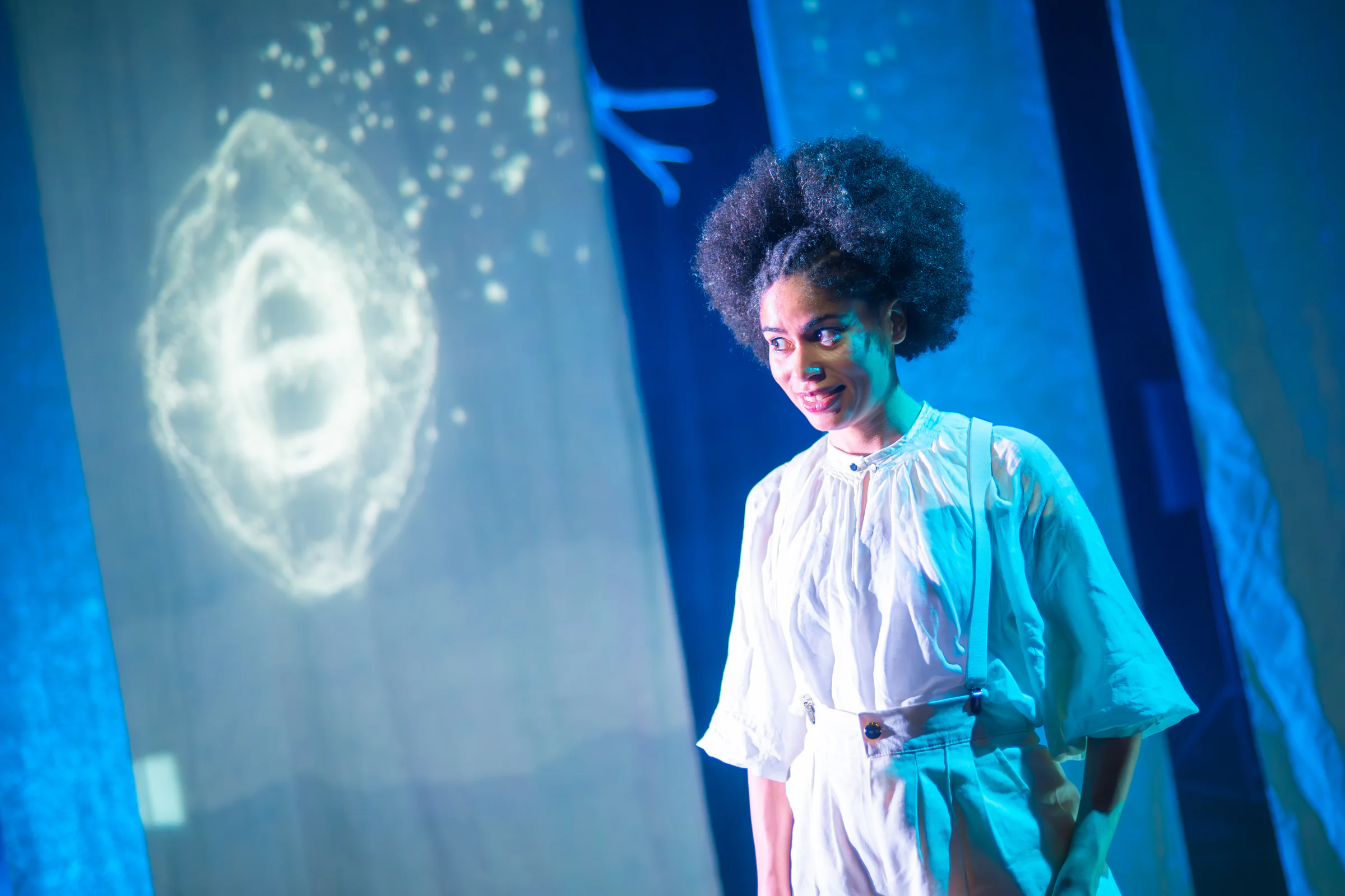 Fay Guiffo smiles on stage beside a circular projected constellation.